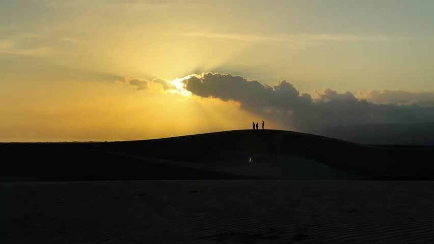Sunset Over Dunes Featuring Silhouetted Figures Captured in a Beautiful Landscape Scene