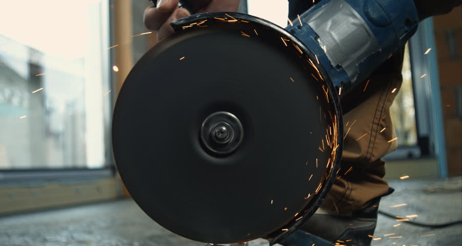 Close-up of spinning angle grinder with sparks flying, high-speed metal cutting in construction setting, focus on power tool in super slow motion 800 fps