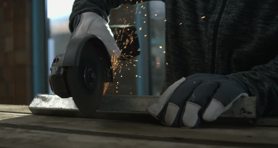 Closeup of angle grinder cutting through metal, sparks flying, focus on craftsman’s gloved hands, precision metalworking, intense concentration, 800 fps slow motion