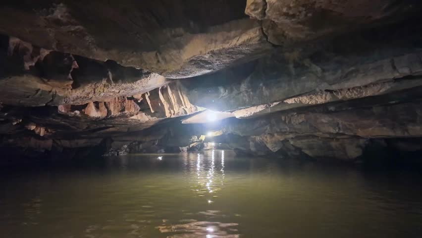 Inside view out of natural cave in Tam Coc scenic spot, Ninh Binh, Vietnam. Tourists float by boat on the river tour to grottoes. Asian natural cave