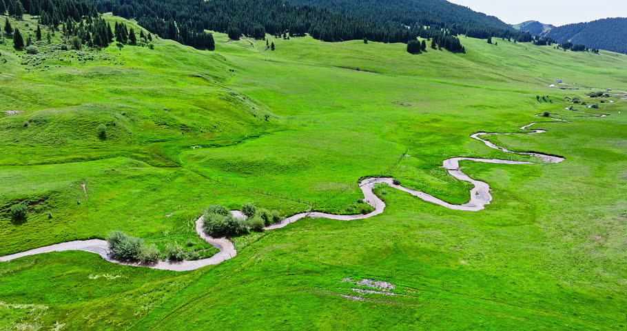 Green grassland and curved river with mountain natural landscape in Xinjiang. Famous grassland pasture scenery in China.