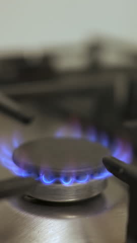 Vertical video of Gas kitchen stove burner with a blue natural flame, close up shot. Economy, price, energy crisis concept.
