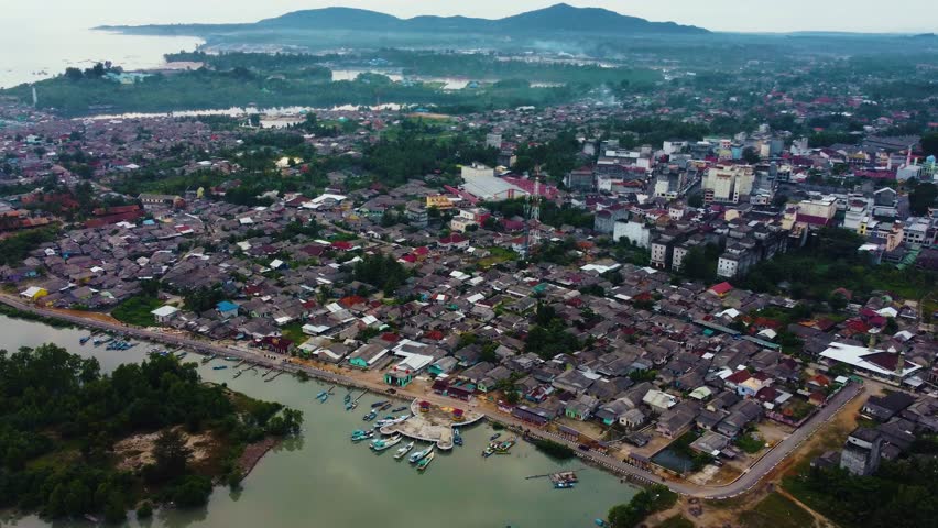 Aerial view of fishing trap net in canel with fisherman urban city village town houses, lake or river. Nature landscape fisheries and fishing tools at Indonesia. Aquaculture farming