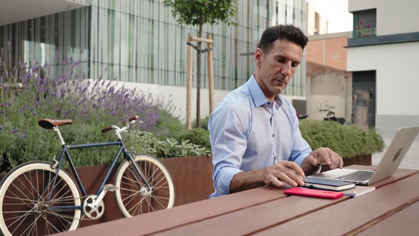 Man working on laptop outside the workplace with bicycle 