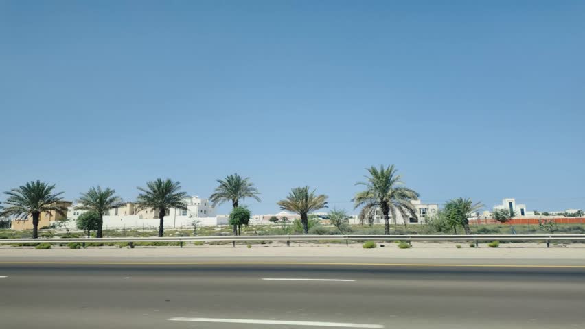 A beautiful road lined with palm trees against a clear blue sky above, Emirates