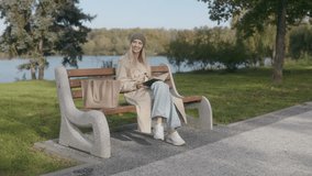 A smiling, blonde woman sits on a bench, reading a book in a scenic autumn park. Dressed for the season, she enjoys the peaceful moment surrounded by natural beauty. - Powered by Shutterstock - Get 15% off with code: PIKWIZARD15