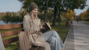 In an autumn park, a blonde woman in her thirties sits on a bench, pulling out a book from her bag. Wearing a hat, she is ready to enjoy some outdoor reading. - Powered by Shutterstock - Get 15% off with code: PIKWIZARD15