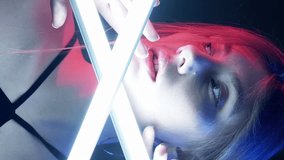 Vertical video. Neon light girl. Futuristic fashion. Disco nightlife. Pink blue color glow woman face white LED lamp illumination on dark. - Powered by Shutterstock - Get 15% off with code: PIKWIZARD15