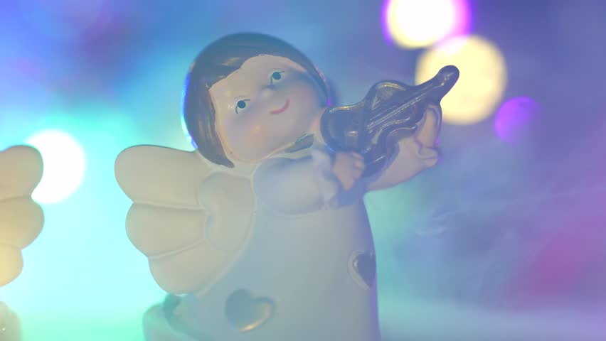 Christmas concept shot with angels playing instruments colored lights with bokeh and fog on the ground