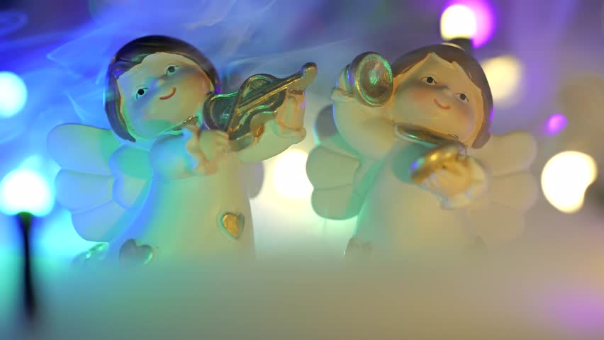 Christmas concept shot with angels playing instruments colored lights with bokeh and fog on the ground