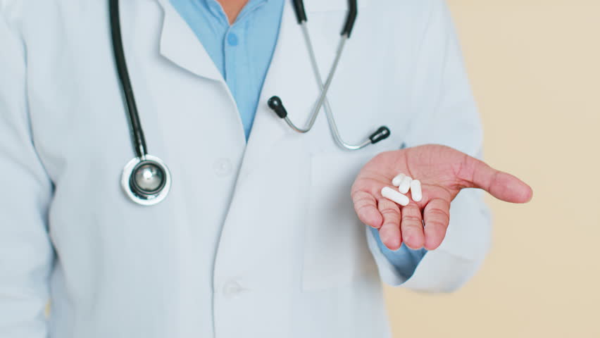 Doctor man show lot of tablet pills white capsules in hand palm, recommends drugs immunization cure treatment. Health care, painkiller. Vitamins for joints, hair, skin, nails. Apothecary pharmacist