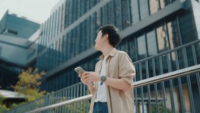 Handsome Asian student using smartphone. A young man standing outdoor happy smiling with holding mobile phone - Powered by Shutterstock - Get 15% off with code: PIKWIZARD15