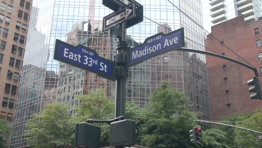 New York City crossroad, Manhattan corner, Madison avenue, street intersection road sign. Midtown central district highrise architecture, United States. One way arrow roadsign, skyscrapers. Low angle.
