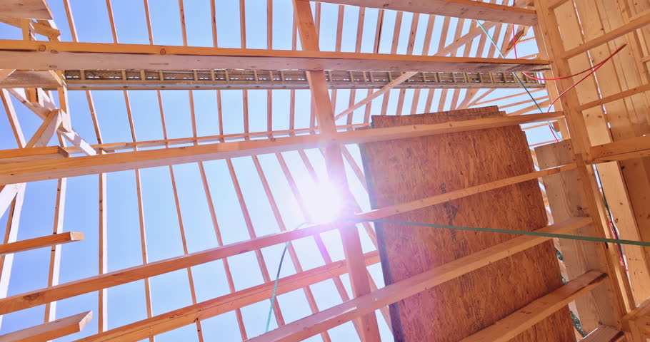 An open roof structure of wooden beams with progressing structural framework for skeletal frames on large construction site