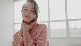 A portrait of a young woman in a warm pink sweater, holding her face softly and smiling. Natural light illuminates the scene, creating a peaceful and cozy ambiance. Elegant Young Woman Posing - Powered by Shutterstock - Get 15% off with code: PIKWIZARD15