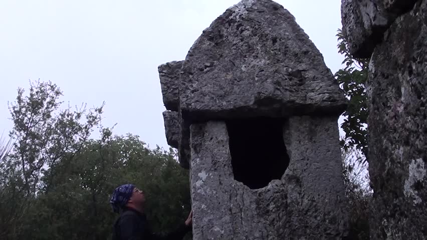 A man in biker suit is touching a tomb