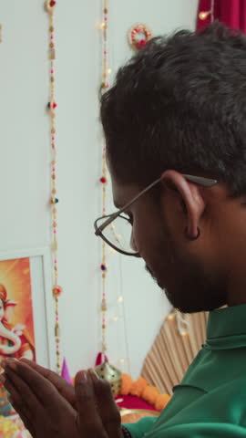 Vertical shot of Indian man in traditional clothes having prayer by altar on Diwali