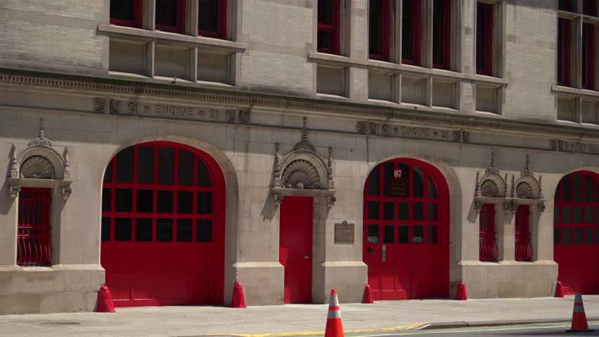 This historic fire station features vibrant red doors and showcases a variety of distinct architectural details