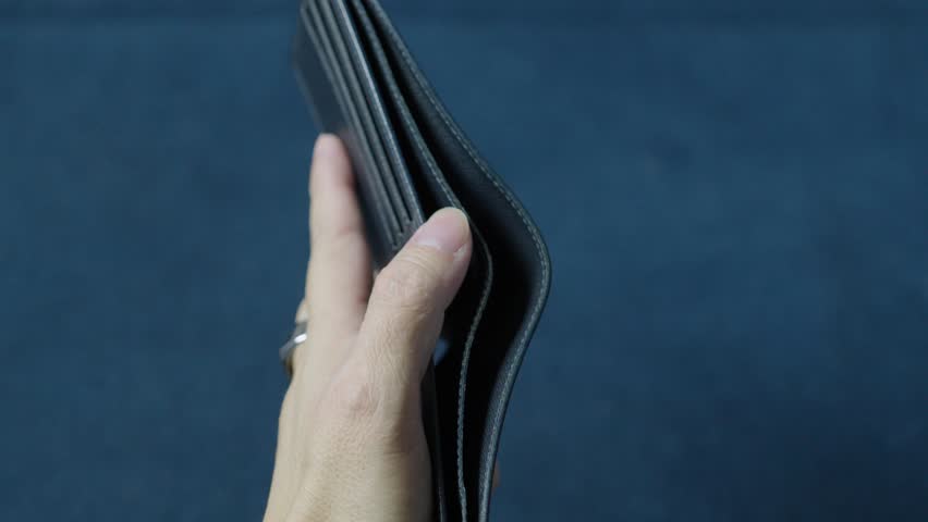 Businessman displaying an empty wallet to illustrate financial struggles