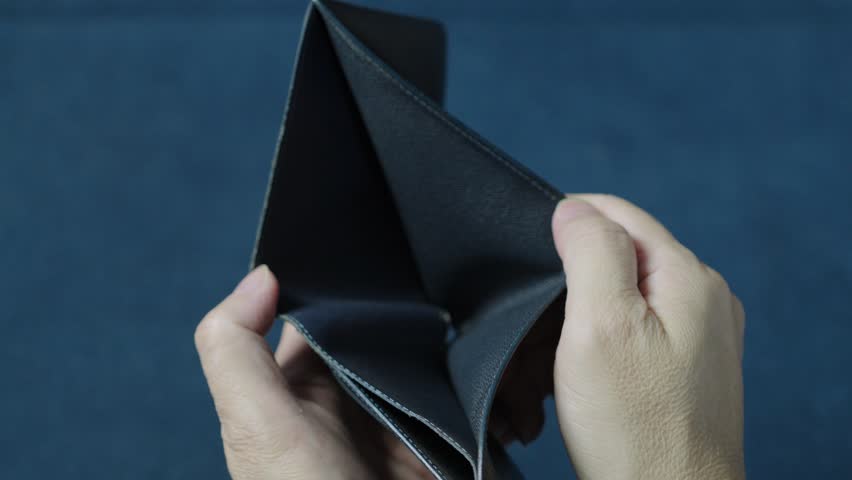 Businessman displaying an empty wallet to illustrate financial struggles