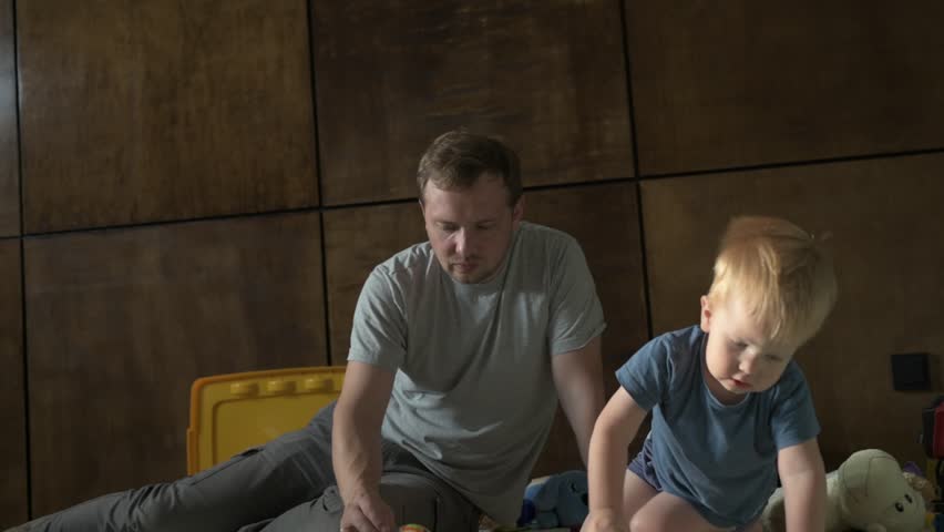 Happy family father and little son spending time together at home, playing games and watching cartoons