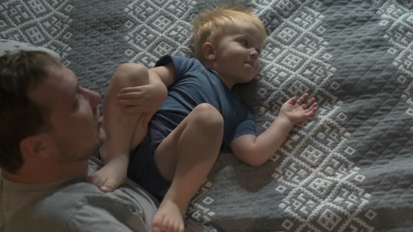 Happy family father and little son spending time together at home, playing games and watching cartoons