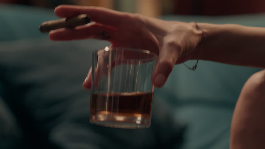 Close up unrecognizable Caucasian woman girl female hand holding cigar and glass alcohol drink addiction bad habit depression mental health problems smoking unhealthy lifestyle indoor home night room