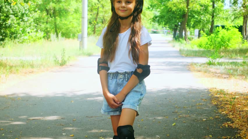 Portrait of Smiling little child girl kid skateboarding at the park. School girl enjoy and having fun outdoor lifestyle practicing extreme sport skateboard skating on summer vacation