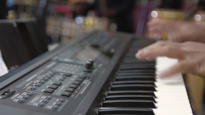 Close-Up of Hands Playing Piano with Drums and Timbales in Background at Outdoor Salsa Party. Primer Plano de Manos Tocando el Piano con Batería y Timbales de Fondo en Fiesta de Salsa al Aire Libre
