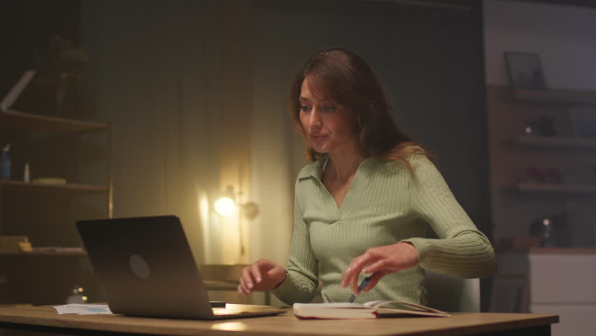 Footage of elegant attractive young Caucasian woman in mint clothes typing on keyboard and looking at screen of laptop. Female student studing economics. Girl preparing for exams and taking notes