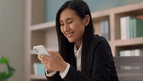 Happy smiling laughing Asian Korean business woman female worker Japanese Chinese businesswoman girl entrepreneur use mobile phone online chatting social media smartphone flirting dating app in office - Powered by Shutterstock - Get 15% off with code: PIKWIZARD15