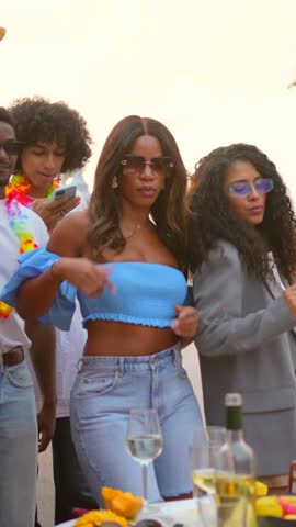 Happy multi-ethnic friends dancing together in a rooftop party at evening