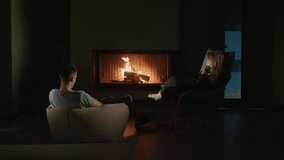 A young couple relaxes in the living room, enjoying the warmth and glow of the fire in the fireplace, creating a cozy and romantic atmosphere. High quality 4k footage - Powered by Shutterstock - Get 15% off with code: PIKWIZARD15