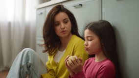 Loving Caucasian family relationship smiling woman female mother sitting kitchen floor talking speak with little girl child kid daughter eating ripe apple fruit indoors. Tenderness childcare parenting - Powered by Shutterstock - Get 15% off with code: PIKWIZARD15