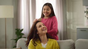 Happy Caucasian little girl child kid daughter sister playing hairdresser with joyful woman female mother mom sibling combing hair laughing family talking laugh having fun together indoor living room - Powered by Shutterstock - Get 15% off with code: PIKWIZARD15