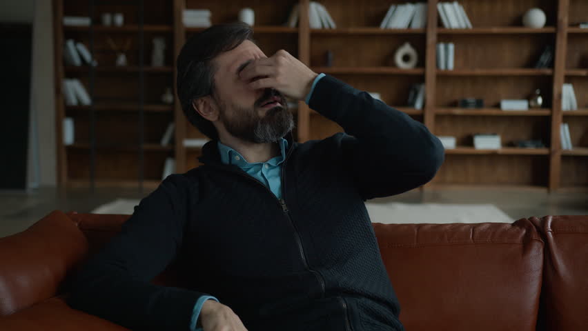 Unhappy frustrated Caucasian male businessman entrepreneur man browsing mobile phone using smartphone read bad news business loss bankruptcy touch eyes suffering eye pain eyestrain irritation indoors