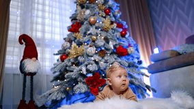 Cute blond baby lying on the fluffy plaid. Low angle view at the sweet child under the Christmas tree. - Powered by Shutterstock - Get 15% off with code: PIKWIZARD15