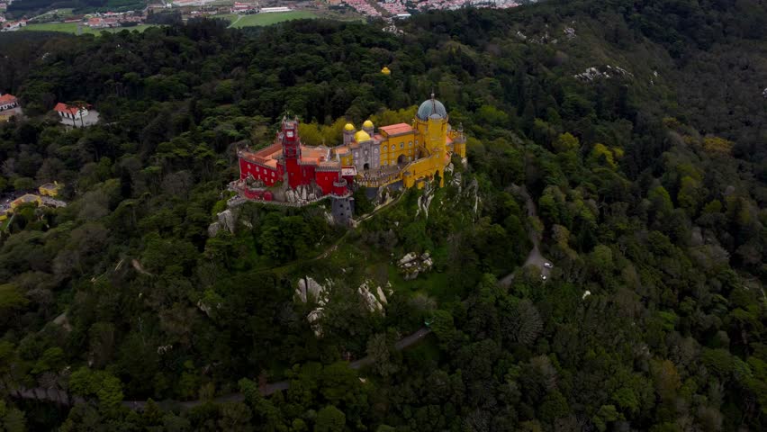 National Palace of Pena situated in Sintra, Portugal. City of Sintra and Lisbon in background. Famous travel destination. The palace is a UNESCO World Heritage Site. Drone going forward. 