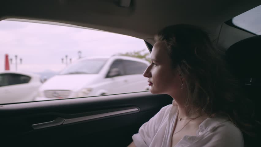Beautiful young Girl lookinh in the Window Enjoying Wind Daytime in a good car