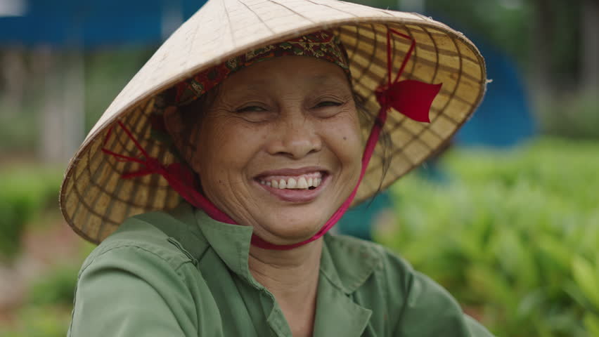 portrait of a mature female farmer wearing a headscarf and a large wicker hat in vietnam