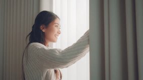 Close up of happy young asian woman opening curtain at home in slow motion, Smiling attractive lady looking outside apartment enjoying dreaming and contemplating feeling hope concept - Powered by Shutterstock - Get 15% off with code: PIKWIZARD15