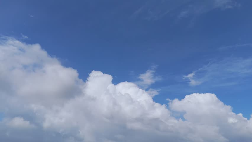 Slow moving white clouds in a bright blue sky