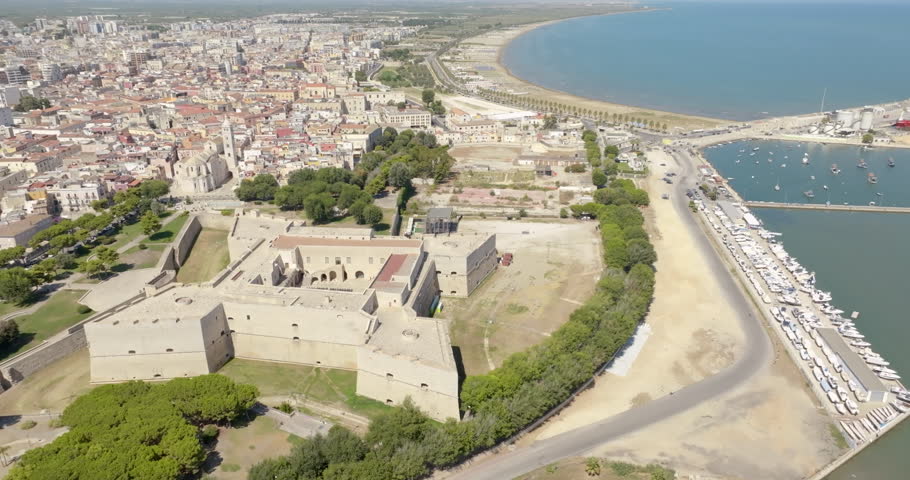 Aerial view of the castle located in Barletta, Puglia, Italy. It was a medieval fortress. In background is the Basilica of Santa Maria Maggiore, cathedral of the city, and the Mediterranean sea.