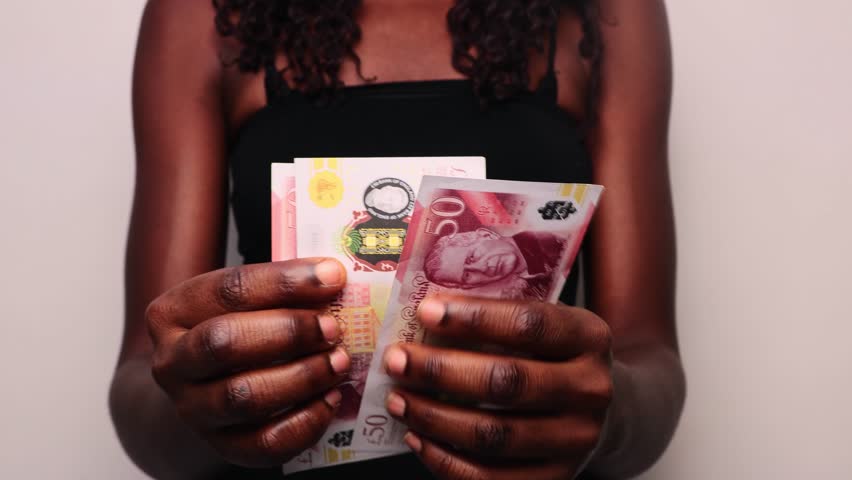 young Black African  woman lady female wearing black tank top standing counting 50 British pounds sterling  notes against white background