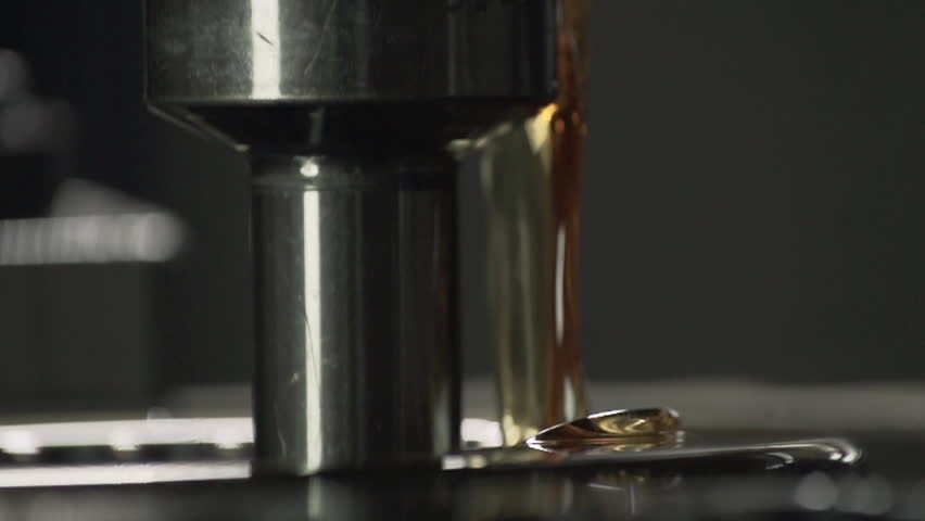 Close-up of huge amounts of oil being poured onto the lathe machine. Industrial lathe machine is covered with greasy machine oil. Automated lathe machine pushing down the oil. Manufacturing plant.