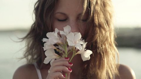 Young woman standing on seashore and smelling flower, slow motion shot at 240fps
 วิดีโอสต็อก