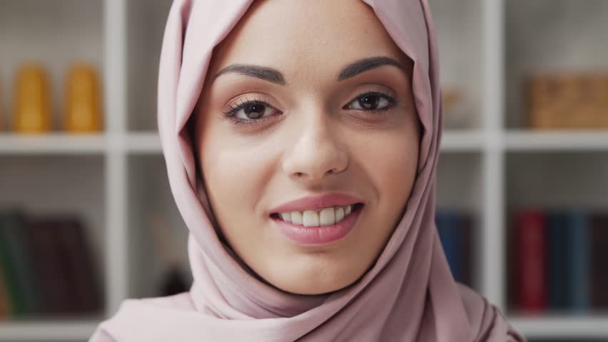 Close-up portrait of young Muslim girl in hijab and protective mask. Sad Middle Eastern woman is sitting in front of the camera at home.