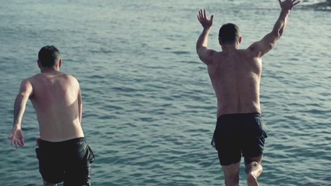 Young men jumping, swimming in the sea, slow motion shot at 240fps
