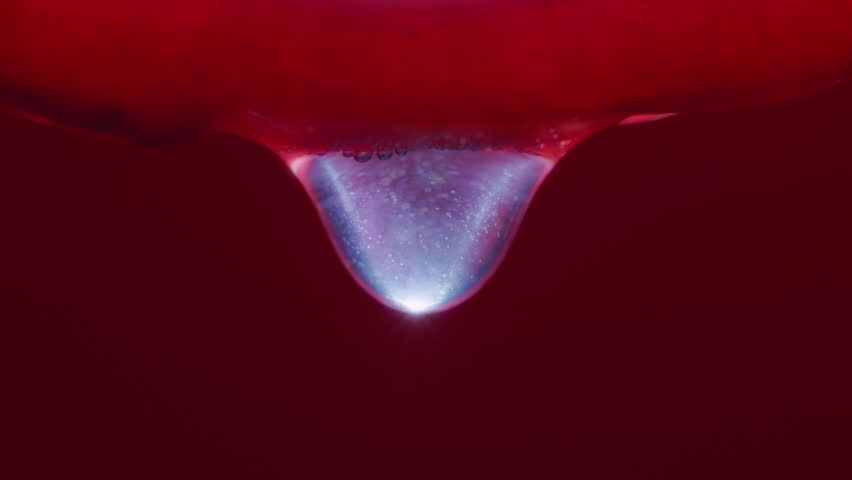 Macro shot of water droplet falling from a dragon fruit slice. Slow motion. 