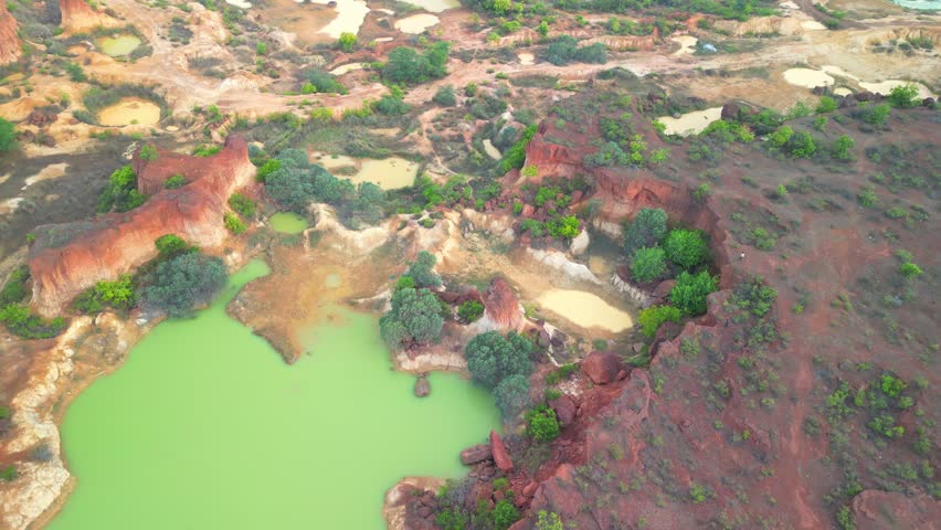 Aerial view of a rugged forest landscape showcasing unique rock formations and a striking green water body.